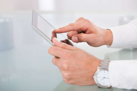 Cropped image of businessman's hands using digital tablet at office desk