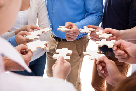 High angle view of people connecting puzzle pieces over white background