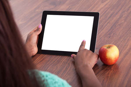 Cropped image of female teacher using digital tablet at classroom desk
