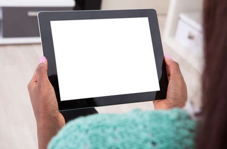 Cropped image of young African American woman holding digital tablet at homeの写真素材