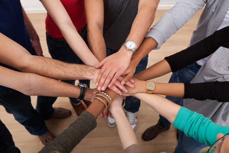 High angle view of multiethnic college students stacking hands in classroom High angle view of multiethnic college students stacking hands in classroom
