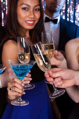 Cropped image of young friends toasting drinks at nightclub