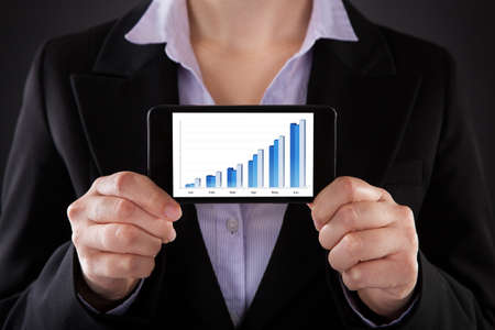Close-up Of Businessperson Showing Graph On Cellphoneの写真素材