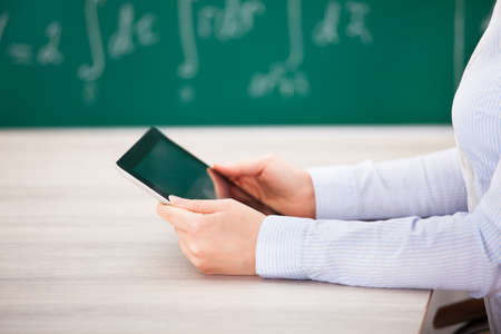 Close-up Of Person Holding Digital Tablet At Deskの写真素材