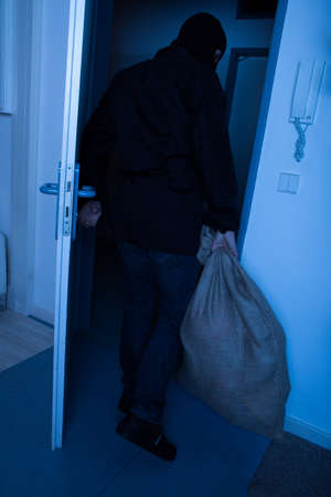 Full length of thief carrying sack while exiting house