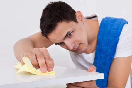 Handsome young man cleaning table with napkin at homeの写真素材