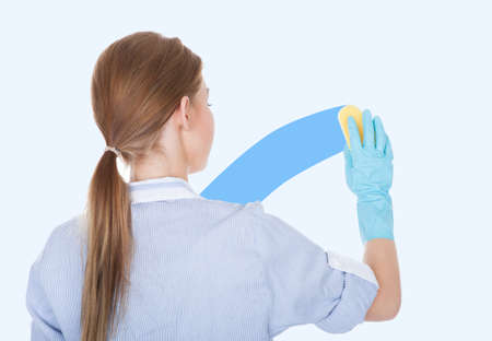 Rear View Of Young Maid Cleaning Glass With Spongeの写真素材