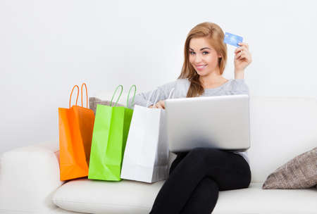 Young Woman Shopping Online Sitting Besides Row Of Shopping Bagsの写真素材