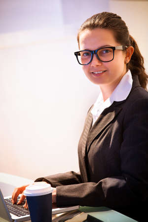 Portrait of smiling businesswoman using laptop at desk in officeの写真素材