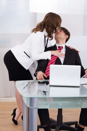 Sensuous secretary seducing businessman at desk in officeの写真素材