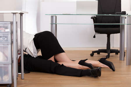 Low section of young business couple getting intimate on floor in officeの写真素材