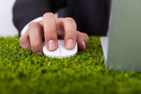 Midsection of businessman using laptop with computer mouse on grass