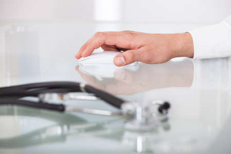cropped image of doctor's hand using mouse in clinic
