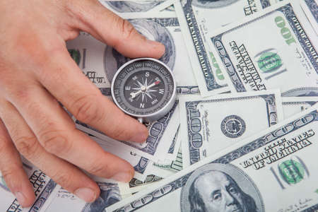 Cropped image of hand holding compass on US paper currencyの写真素材