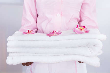 Smiling young female housekeeper carrying towels in hotelの写真素材
