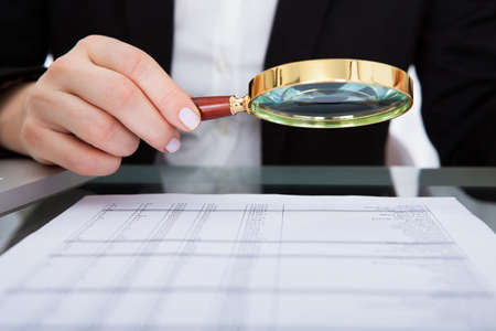 Businesswoman Looking At Document Through Magnifying Glassの写真素材