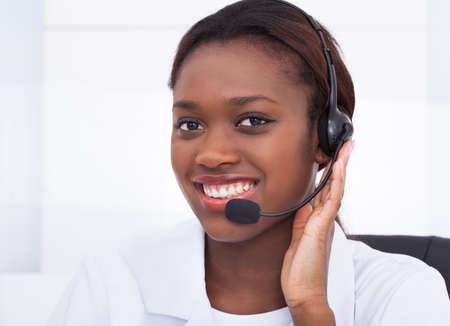Close-up portrait of confident receptionist using headset in hospital