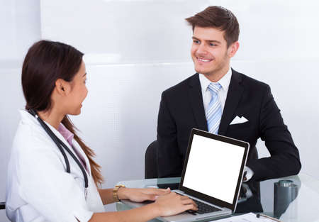 Side view of businessman consulting female doctor in clinic