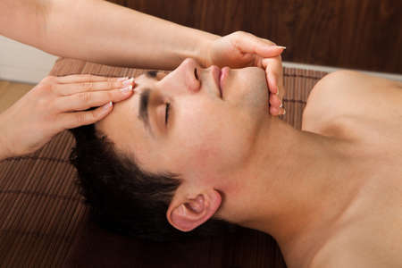Side view of young man receiving head massage from massager in spaの写真素材