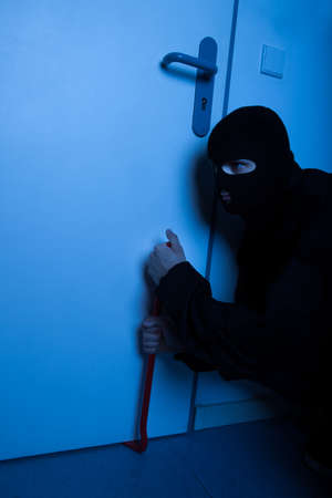 Thief opening door with crowbar during house breakingの写真素材