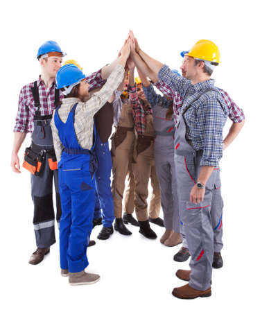 Diverse multiethnic group of artisans giving a high five gesture as they stand in a circle showing their commitment and motivation for a team project  isolated on whiteの写真素材