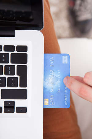 Cropped image of man inserting credit card in laptop at homeの写真素材