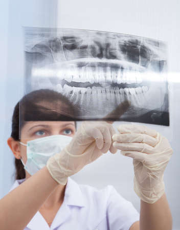 Young female stomatologist pointing at jaw Xray in clinic