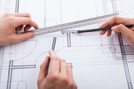 Hands of architects making blueprint at desk in office