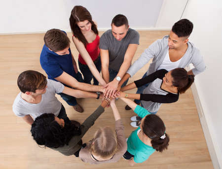 High angle view of multiethnic college students stacking hands in classroom