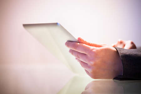 Cropped image of businesswoman holding digital tablet at desk in office