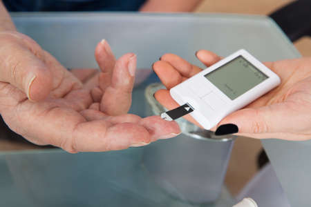 Cropped image of doctor checking glucose level in diabetic patient at clinic