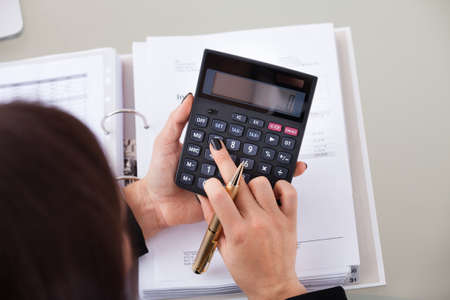 High angle view of female accountant calculating tax at desk in office