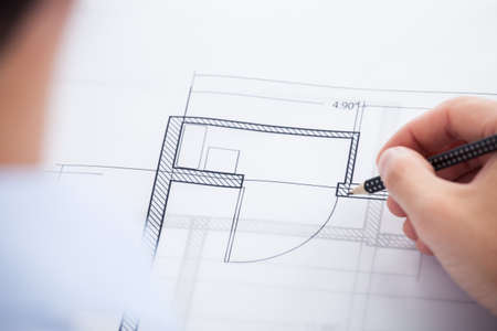 Cropped image of architect working on blueprint in office