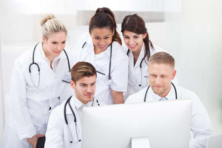 Team of doctors using desktop PC together at desk in clinicの写真素材