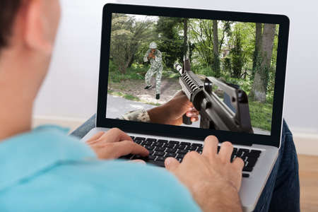 Closeup of man playing action game on laptop at homeの写真素材