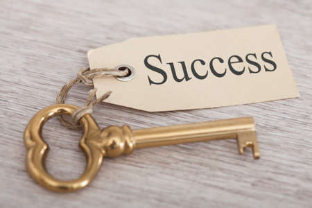 Golden key with success tag on wooden tableの写真素材