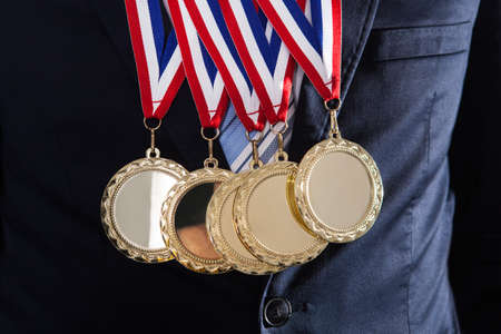 Midsection of businessman wearing gold medals against black backgroundの写真素材