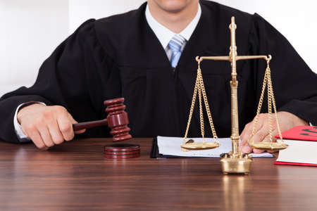 Midsection of male judge with mallet and weight scale at table in courtroomの写真素材