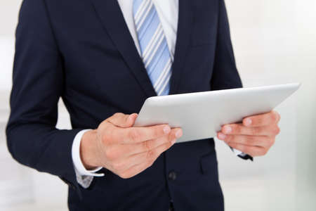Midsection of businessman holding digital tablet in office