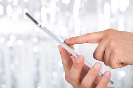 Cropped image of man touching digital tablet indoors