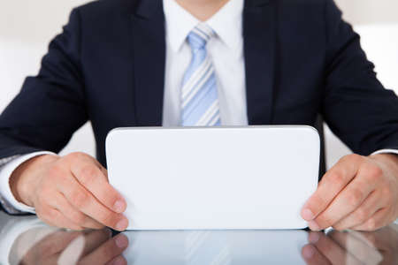 Midsection of businessman using digital tablet at desk in officeの写真素材