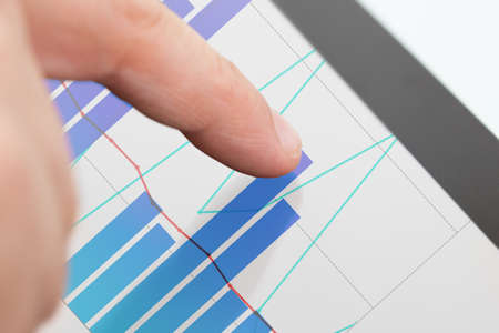 Cropped image of businessman analyzing graphs on digital tabletの写真素材