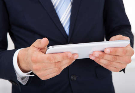 Midsection of businessman holding digital tablet in office