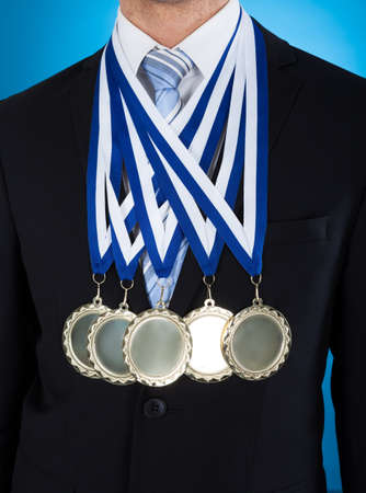 Midsection of young businessman wearing medals over blue backgroundの写真素材