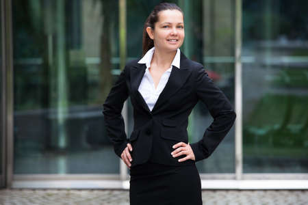 Portrait of confident businesswoman standing with hand on hip outside office buildingの写真素材