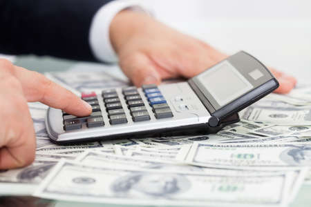 Cropped image of businessman calculating money at desk in officeの写真素材