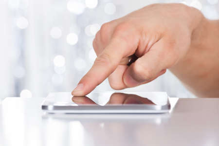 Cropped image of man touching smartphone at tableの写真素材