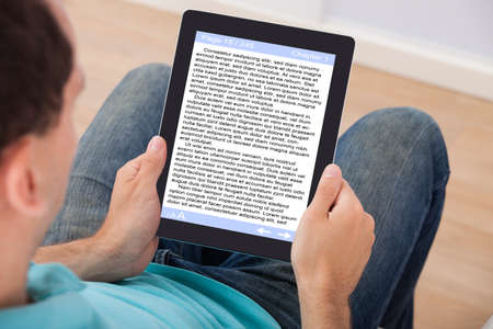 Man reading eBook on digital tablet at home