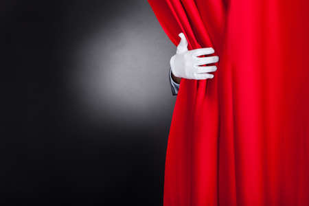 Cropped image of magician opening red stage curtainの写真素材