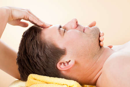 Side view of young man receiving forehead massage in spaの写真素材